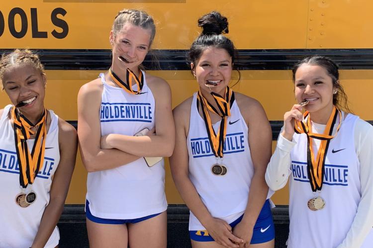ARE THE HOLDENVILLE HIGH SCHOOL 4X400 RELAY TEAM MEMBERS HINTING THAT IT’S TIME TO EAT? The girls are trying to munch on their hard earned medals and they did accumulate several! The relay team members are Destiny Jennings, Dixie Gamble, Ryleigh Tiger and Chloe Tiger!